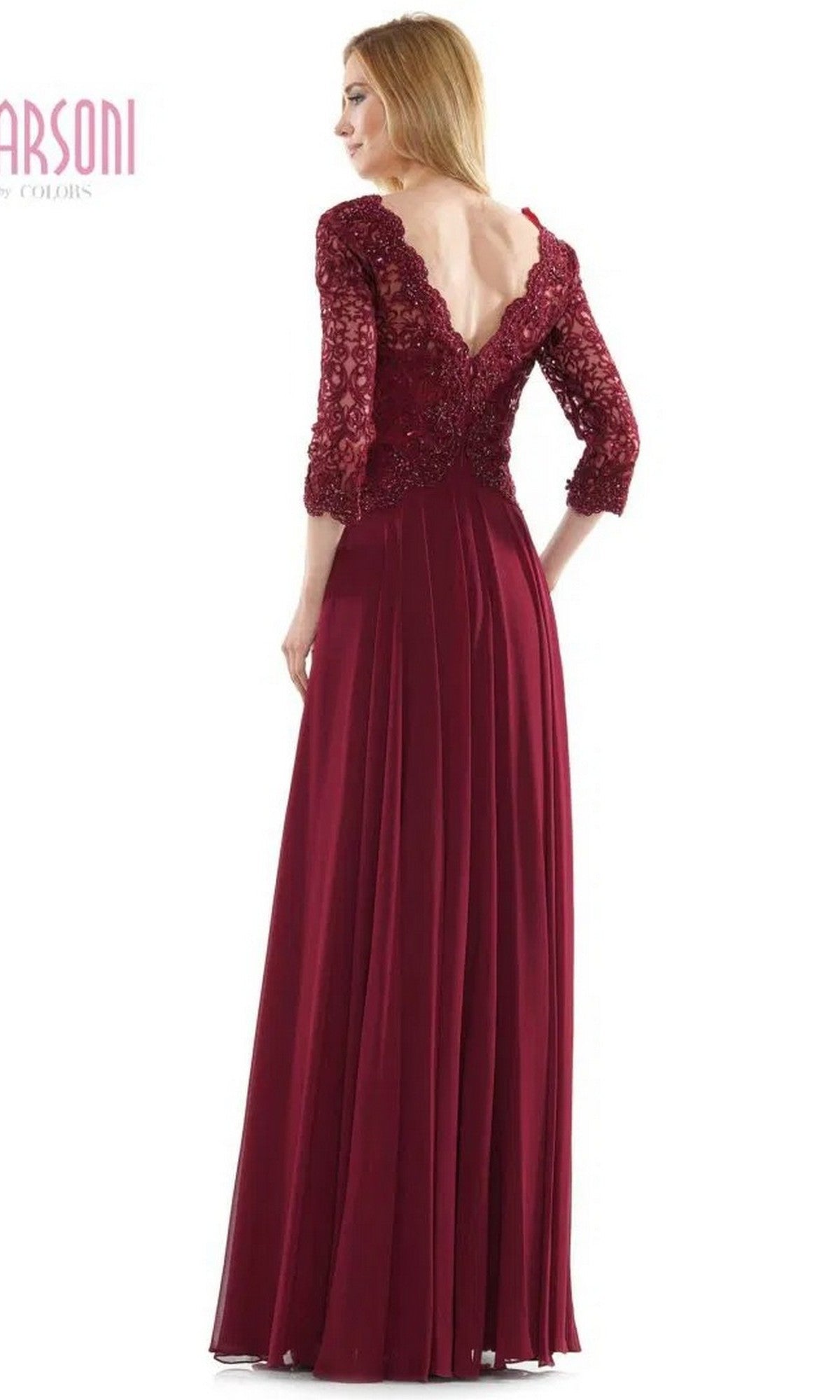 A woman stands facing away, wearing the Marsoni M225 long formal dress—floor-length, burgundy, with lace sleeves, a lace-embroidered bodice, and a V-shaped back.